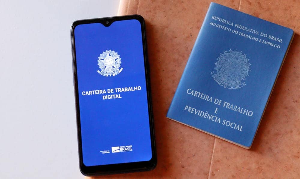 carteira de trabalho ao lado do celular com app da ctps digital aberto