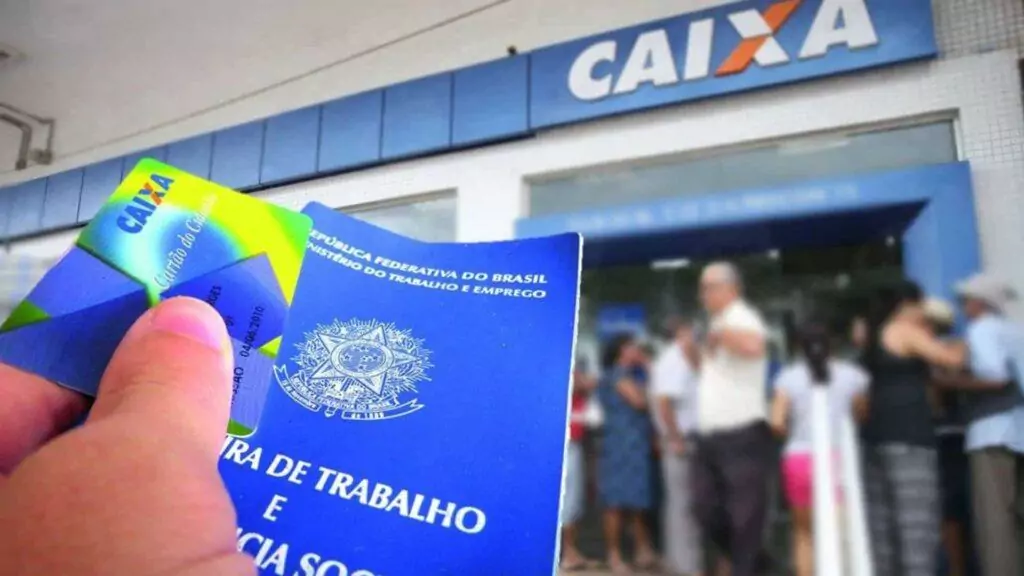 mão segurando carteira de trabalho e cartão do cidadão em frente ao banco caixa