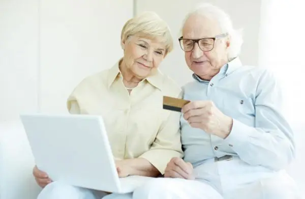 casal de idoso com cartão de crédito e laptop