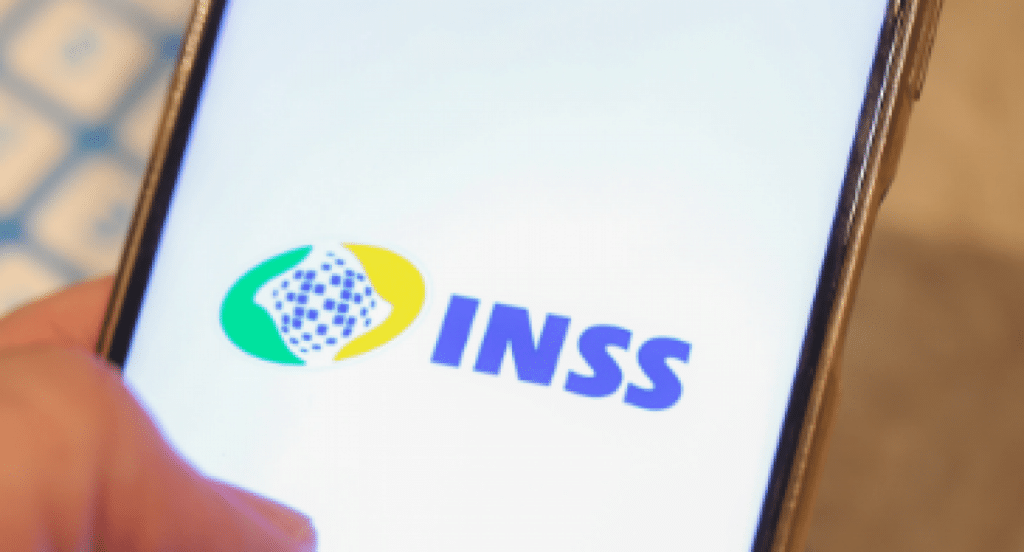Foto de mão segurando smartphone com aplicativo do INSS aberto.