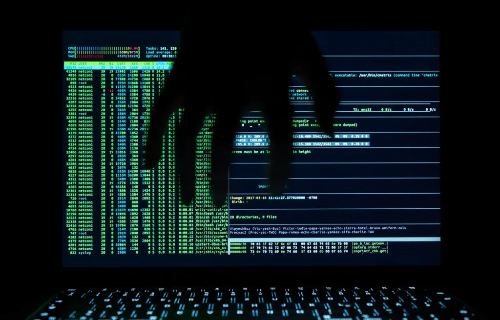 imagem escura de um notebook com informações de segurança com uma mão na frente