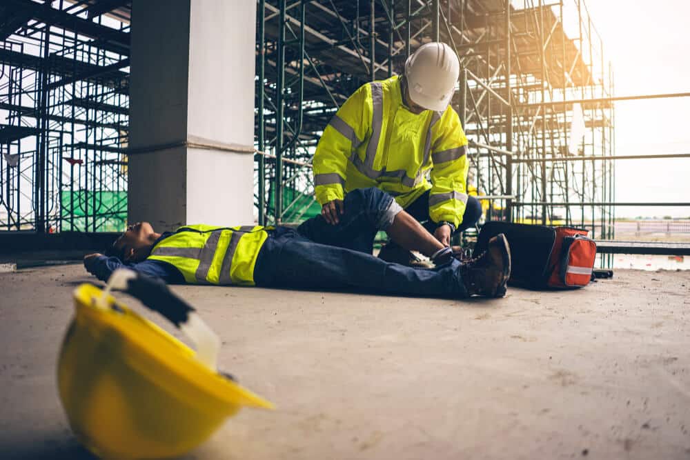 trabalhador deitado no chão e machucado por ter tido acidente de trabalho