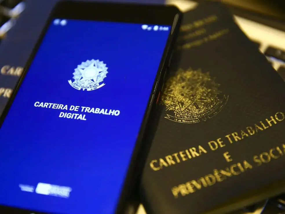 carteira de trabalho ao lado de celular com a ctps digital aberta
