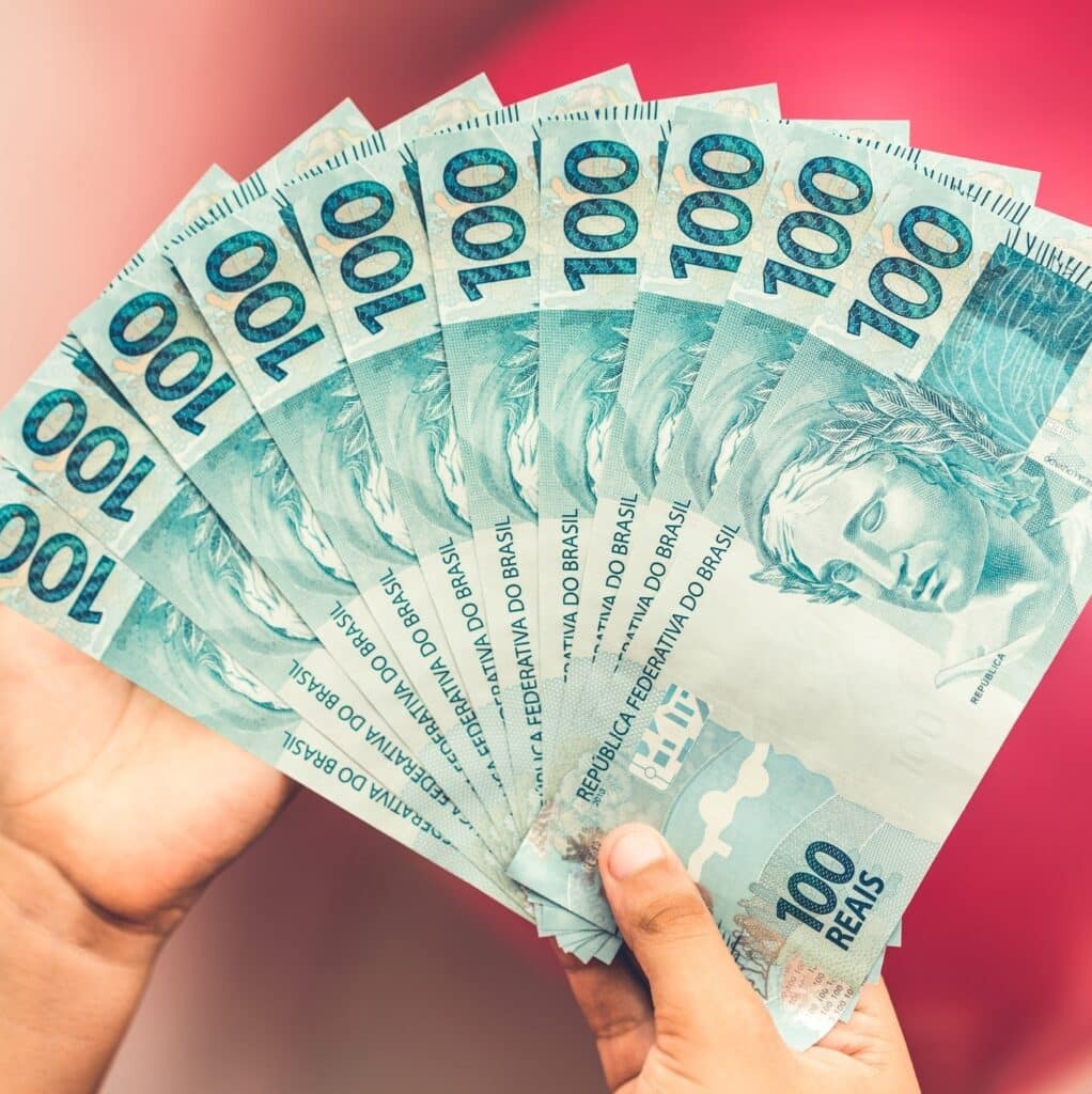 imagem com mãos segurando notas de cem reais para falar sobre o imposto sobre os mais ricos.