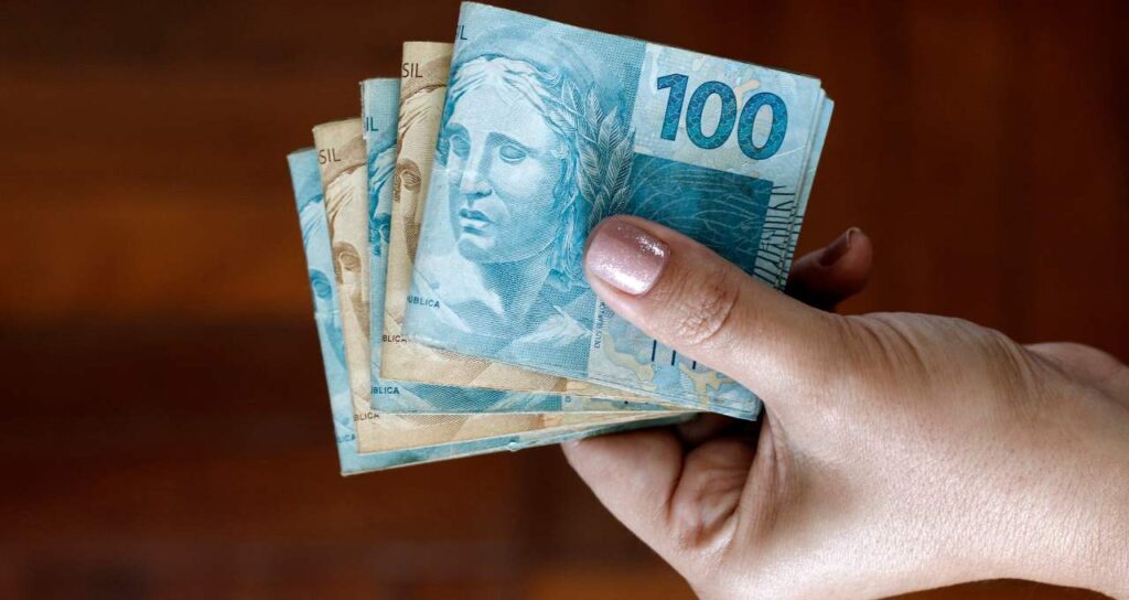 mãos com dinheiro em reais liberados pelo saque FGTS calamidade