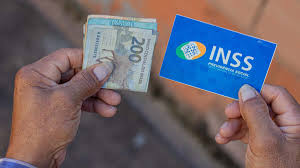 maos segurando dinheiro e um cartao do inss