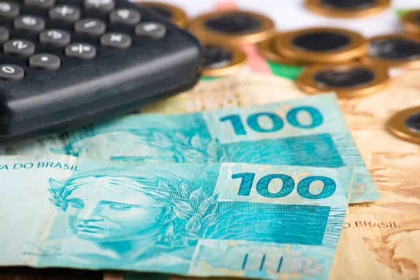 notas de cem reais com uma calculadora e moedas