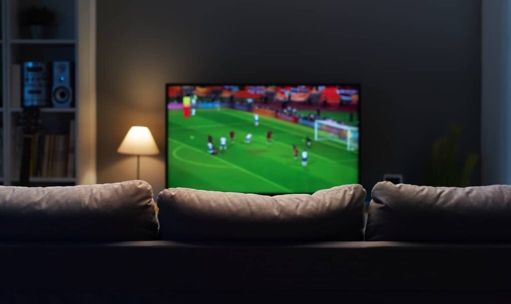 tv ligada em jogo de futebol em uma sala de uma casa