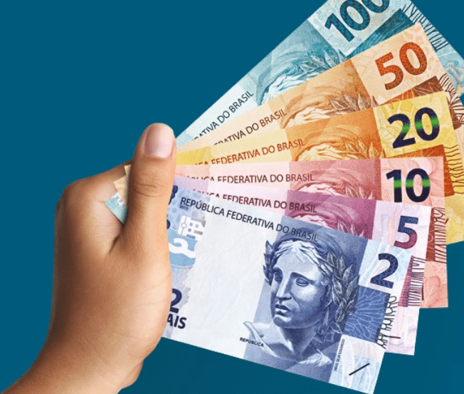 pessoa segurando notas de reais