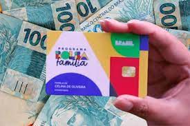mão segurando cartão do bolsa família e dinheiro
