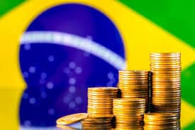 imagem da bandeira do brasil com moedas de dinheiro para falar da projeção de déficit.