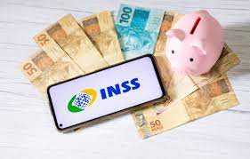 imagem com dinheiro espalhado, com um cofre de porquinho rosa e um celular com o logo do INSS na frente para falar sobre o novas regras da aposentadoria.