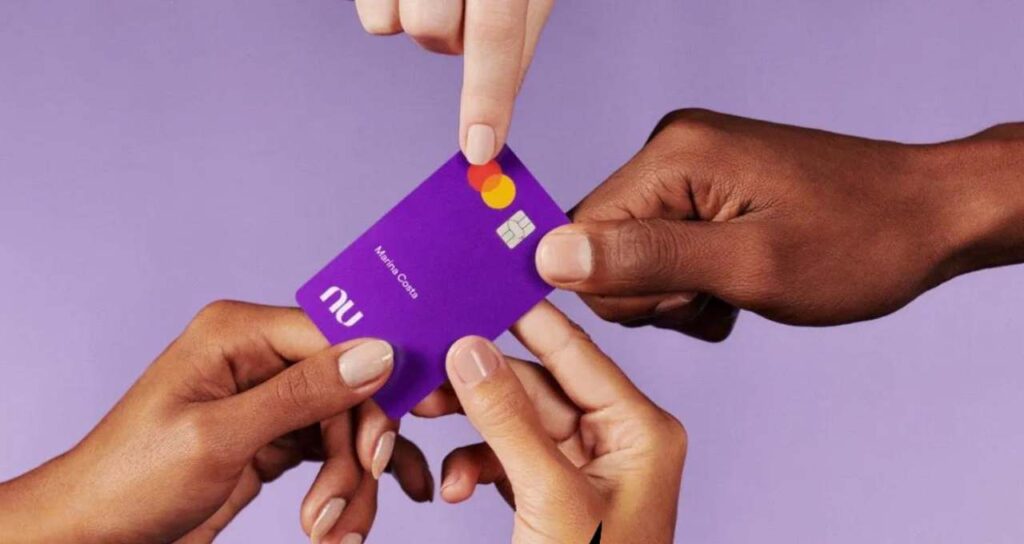várias mãos segurando o cartão do nubank