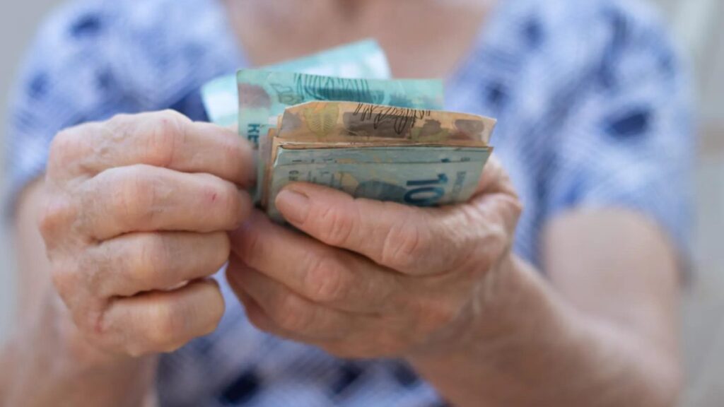 Mão contando várias notas de 100 e 50 reais