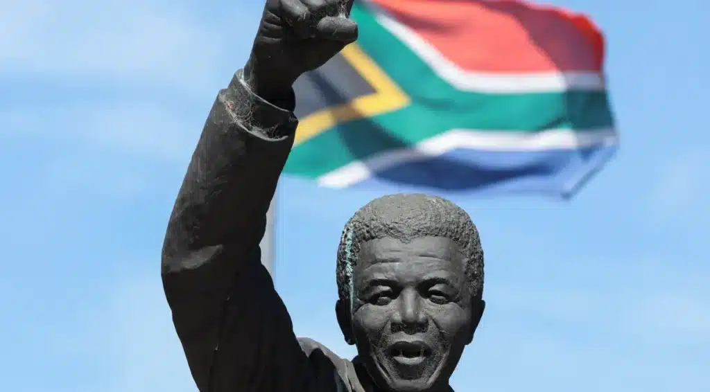Bandeira da África do Sul atrás de estátua de Nelson Mandela. (Fonte: Reprodução Google).