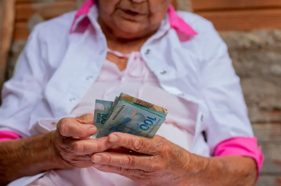idosa segurando notas de 100 reais