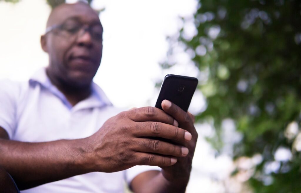 idoso, negro, careca, utilizando um smartphone