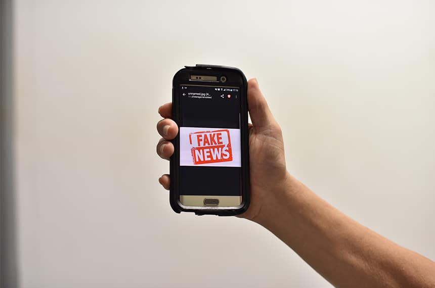 celular aberto na tela que está escrito fake news