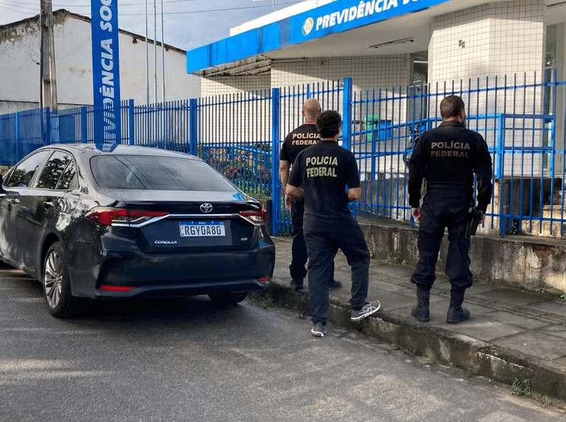 viatura e agentes das polícia federal em frente a um edifício da previdência social