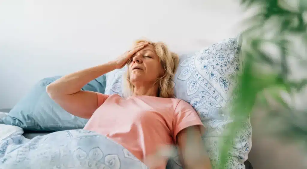 Mulher deitada na cama com menopausa. (Fonte: Reprodução OLEKSANDRA TROIAN/GettyImages)
