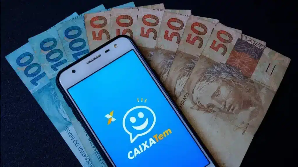 celular aberto no caixa tem ao lado de muitas cédulas de 50 reais e 100 reais