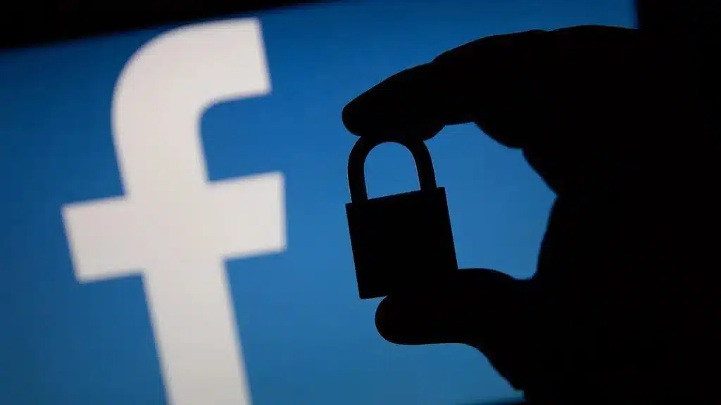 mão segurando cadeado em frente o ícone do facebook