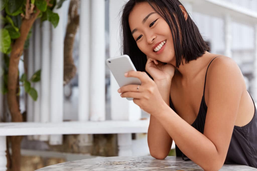 mulher feliz, mexendo no celular