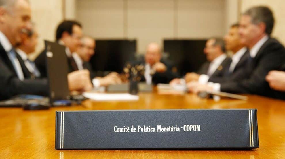 foto de reunião do COPOM com foco em placa onde está escrito 'Comitê de Política Monetária - COPOM'