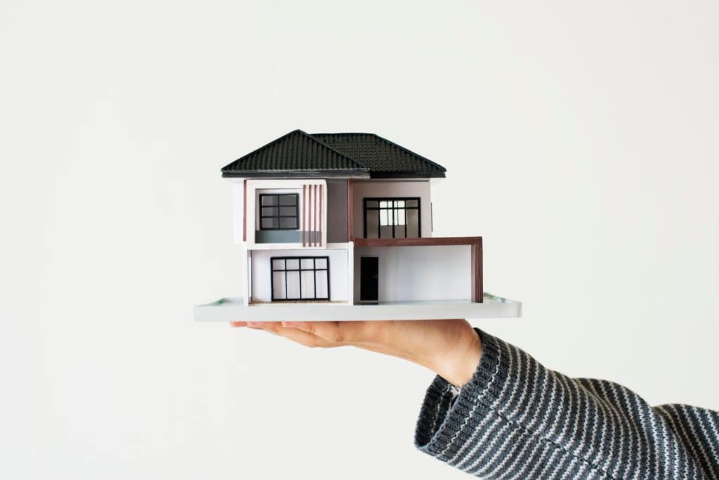 mão segurando uma casa de maquete 