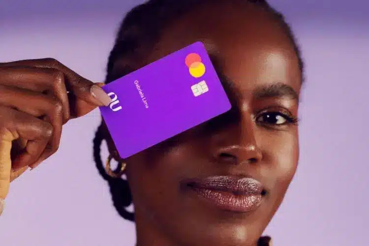 Mulher segurando cartão roxo do Nubank. (Fonte: Nubank).