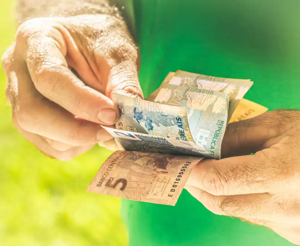 mão segurando dinheiro advindo do Auxílio de 1500 para mei. (Fonte: shutterstock).