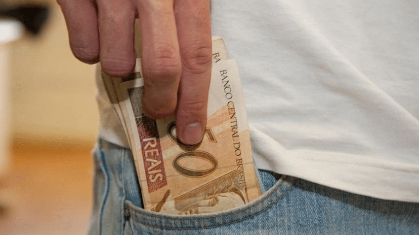 pessoa colocando dinheiro no bolso